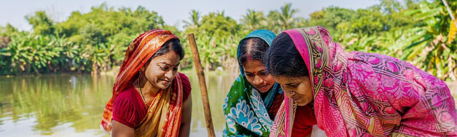 Women pouring water into a large container