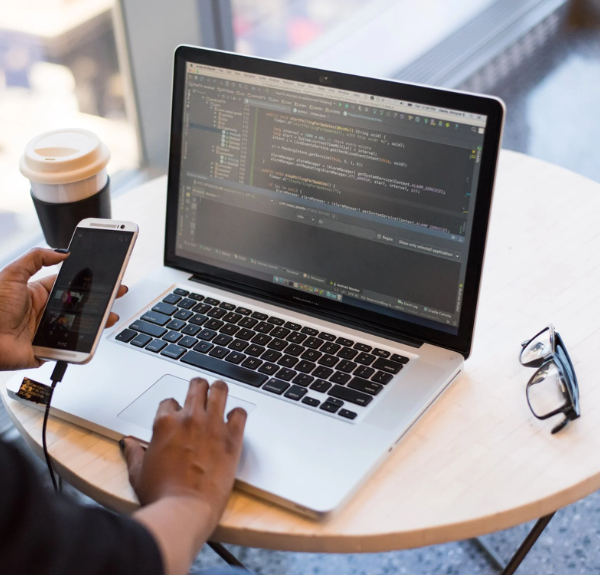 Coding language on a laptop, woman with a phone in her hand.